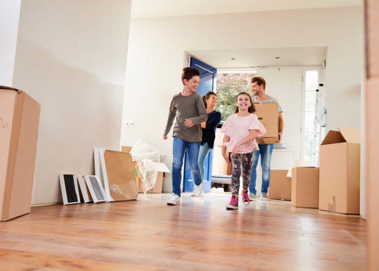 Family Carrying Boxes Into New Home On Moving Day